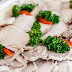 Schab gotowany w majonezie, pokrojony w plastry, ozdobiony natką pietruszki i papryką. Pyszne danie na przyjęcie.