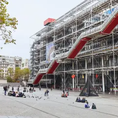 Centrum Pompidou w Paryżu z czerwonymi schodami ruchomymi i ludźmi na placu.