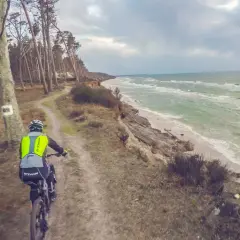 Rowerzysta na ścieżce przy klifie, w tle morze. Trasa rowerowa w okolicach Słupska.