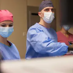 Chirurdzy w maseczkach i fartuchach podczas operacji.
