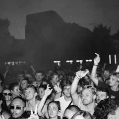 Folla in delirio a un concerto, con mani alzate e luci soffuse. Marco festa dj fa ballare tutti.