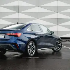 Eleganckie, nowe Audi A3 w kolorze granatowym prezentuje się stylowo na tle nowoczesnej architektury.
