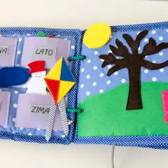 Kolorowa książka sensoryczna dla dziecka z motywami pór roku: wiosna, lato, jesień, zima. Jest tu bałwanek, latawiec, drzewo i motyl.