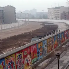 Kolorowy mur berliński, świadectwo czasów, kiedy zbudowano mur berliński, z ludźmi spacerującymi po jego drugiej stronie.
