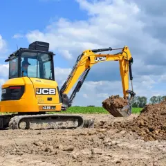 Żółte mini koparki JCB pracują na budowie, kopiąc ziemię.