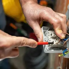 Elettricista collega cavi a una presa, mostrando le differenze tra i tipi di connessione.