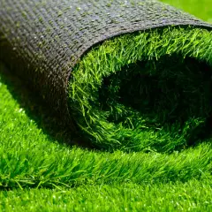 A rolled-up section of artificial grass lies on a bed of lush green turf, hinting at how to install artificial grass for a perfect lawn.