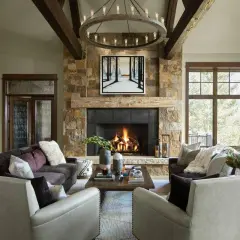 A cozy living room with a stone fireplace, exposed wooden beams, and plush seating embodies rustic interior design.