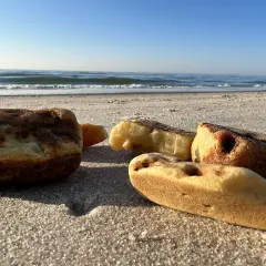 Kilka kawałków bursztynu leży na piaszczystej plaży. Warto wiedzieć, jak rozpoznać bursztyn na plaży, by nie przegapić takiego skarbu.