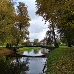 Jesienny park w Choroszczy z mostkiem nad kanałem i pałacem w tle.
