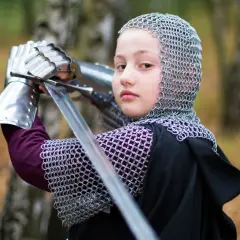 Dziecko w zbroi kolczej i z mieczem, przygotowujące się do walki.