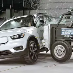 En vit Volvo XC40 krocktestas mot en barriär. Glas splittras och bilen deformeras vid kollisionen.