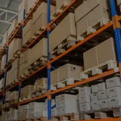 Wysokie regały magazynowe wypełnione kartonami na paletach. To magazyn półotwarty przykłady organizacji przestrzeni.