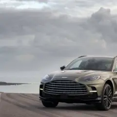 Aston Martin DBX 707 na tle pochmurnego nieba i morza. Luksusowy SUV prezentuje się majestatycznie na pustej drodze.