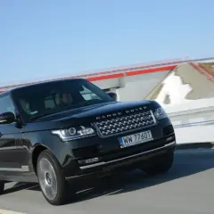 Czarny Range Rover Vogue pędzi po drodze, za nim śnieżne krajobrazy i błękitne niebo.