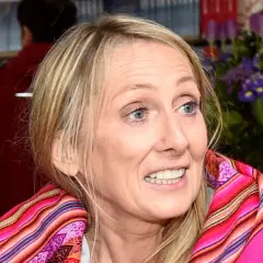 Beata Pawlikowska z kolorowym szalem na tle książek i kwiatów.