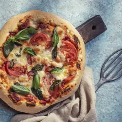 Pyszna pizza na cieście bez drożdży, z pomidorami i bazylią, gotowa do podania.