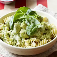 Pyszny makaron z kurczakiem w kremowym sosie pesto, udekorowany świeżym szpinakiem. Idealny obiad dla całej rodziny.