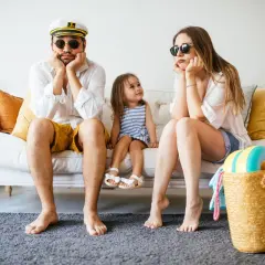 Famille dépitée sur un canapé, valise rouge prête. Annulation location vacances cas de force majeure, les vacances rêvées s'envolent.