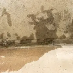 Feuchte Wand und nasser Boden im Keller nach starkregen. Grundwasser dringt ein und hinterlässt dunkle Flecken.