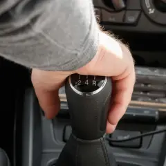 Mano cambiando de marcha en un coche, se escucha un ruido al girar el volante en movimiento a la derecha.