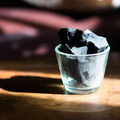 Kawałki węgla aktywnego w szklance, ukazujące jego naturalne właściwości oczyszczające.