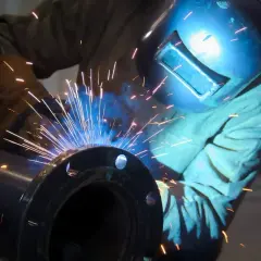 Spawanie żeliwa: iskry sypią się podczas precyzyjnej pracy spawacza w masce ochronnej, łączącego metalowe elementy.