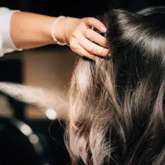Hårstylist fixar en elegant edgar hairstyle med hårspray.