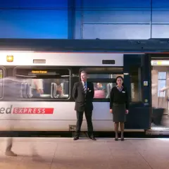 Pociąg Stansted Express na stacji. Pracownicy obsługi i pasażerowie wsiadają i wysiadają. Szybki transport z lotniska do centrum Londynu.