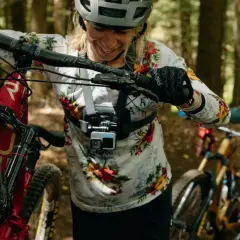 Kamera sportowa na kask rejestruje emocje z górskiej trasy. Kobieta z rowerem w lesie, gotowa na przygodę.