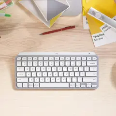 Escritorio con varios tipos de teclado, ratón, bolígrafo, cubos y muestras de color Pantone.