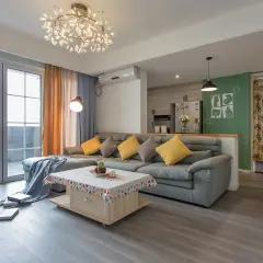 Nowoczesne oświetlenie pokoju tworzy przytulną atmosferę. W centralnym punkcie wisi designerska lampa, a obok niej stojąca lampa rzuca ciepłe światło na szarą sofę.
