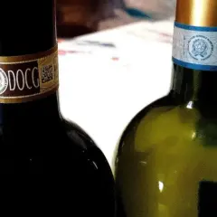 Dwie butelki włoskich win DOCG, czerwonego i białego, gotowe do degustacji.