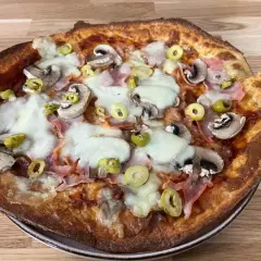 Chrupiący spód do pizzy z pieczarkami, szynką i oliwkami, polany ciągnącym się serem.