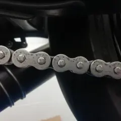 La catena di una moto mostra segni di ruggine, indicando la necessità di manutenzione.