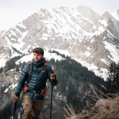 Mężczyzna w kurtce z ociepliną **Primaloft Gold** wspina się po górskim szlaku.