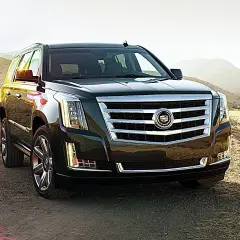 Ciemny Cadillac Escalade na tle gór i suchej trawy.
