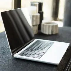 Otwarty MacBook na czarnym blacie. Dowiedz się, jak zmienić język w MacBook, aby dostosować go do swoich potrzeb.
