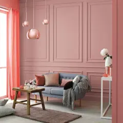 Przytulne, ciepłe wnętrza aranżacje w odcieniach różu i koralu. Sofa, stolik, poduszki i zasłony tworzą przytulną atmosferę.