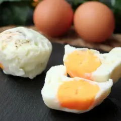 Huevos cocidos en microondas, uno entero y otro partido mostrando la yema naranja. Dos huevos enteros al fondo.