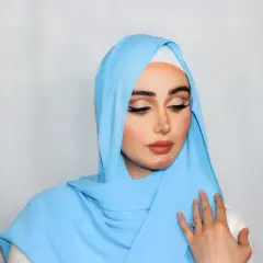 Młoda kobieta w błękitnym hidżabie, z eleganckim makijażem, pokazuje, kto nosi hidżab z dumą i pięknem.