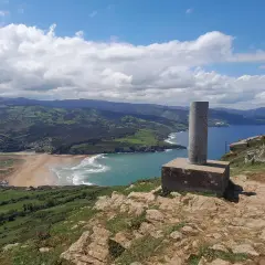 Vistas desde Punta Lucero: costa verde, playa dorada y mar azul bajo un cielo nublado.