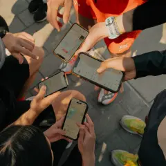 Grupa biegaczy analizuje swoje wyniki na telefonach. Widać mapy tras i statystyki aktywności, typowe dla aplikacji **Strava po polsku**.