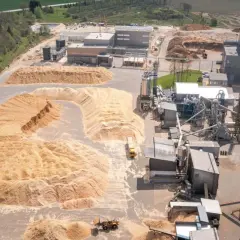 Vue aérienne d'une usine de transformation du bois avec d'énormes tas de sciure. Le prix de la sciure de bois à la tonne est un facteur clé pour cette industrie.