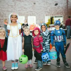 Dzieci w strojach na Halloween, gotowe na psikusy i zbieranie słodyczy. Wśród nich księżniczka, Kapitan Ameryka i inne postacie.