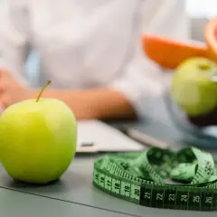Zielone jabłko, miarka i owoce na stole. Wizyta u dietetyka, wsparcie Novo Nordisk w dbaniu o zdrowie.