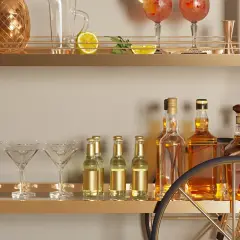Elegancki barek w salonie z butelkami whisky, kieliszkami do martini i złotym dzbankiem w kształcie ananasa. Pomysły na stylowe przyjęcie.