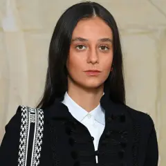 Joven con estilo cayetano, luce un blazer oscuro con detalles de pasamanería y una camisa blanca. Su bolso Dior complementa el look.