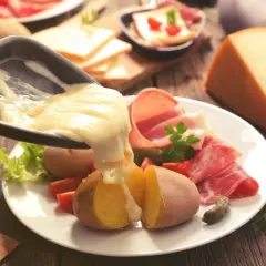 Raclette, le meilleur plat français, avec pommes de terre, charcuterie et fromage fondu. Un délice réconfortant.