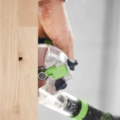 Main d'un artisan utilisant la défonceuse Festool OFK 500 pour travailler le bois avec précision.